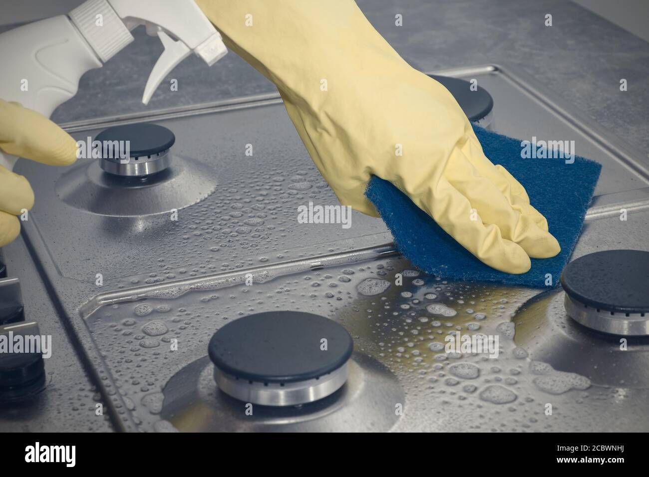 Hands in yellow gloves washing the gas stove Stock Photo Alamy
