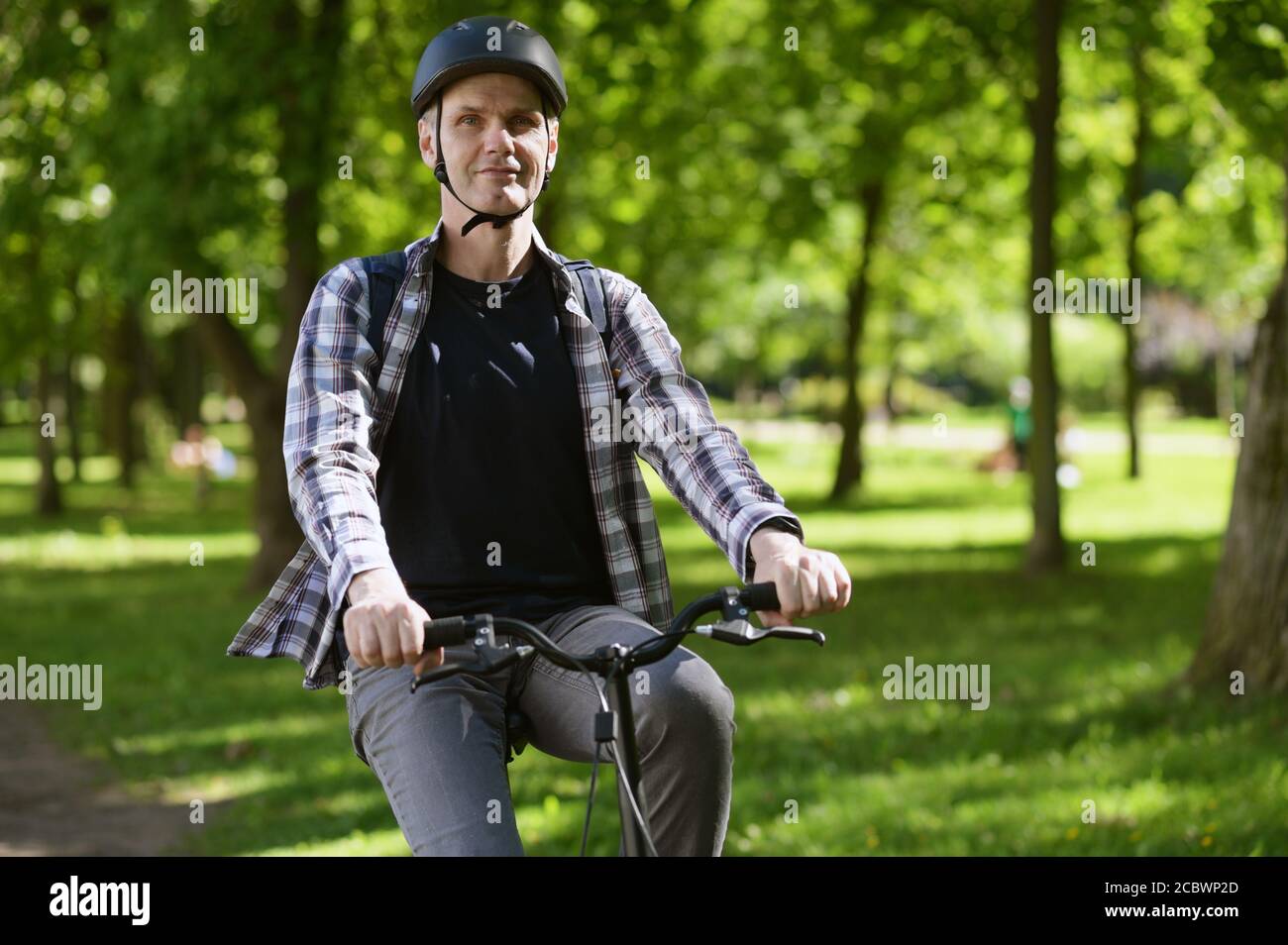 Mature Caucasian man in a bicycle helmet on his bike in a city park Stock Photo
