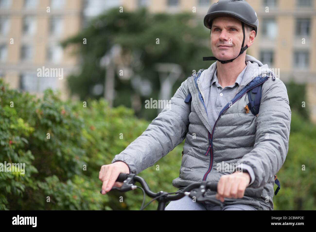 Mature Caucasian man in a bicycle helmet on his bike in a city Stock Photo