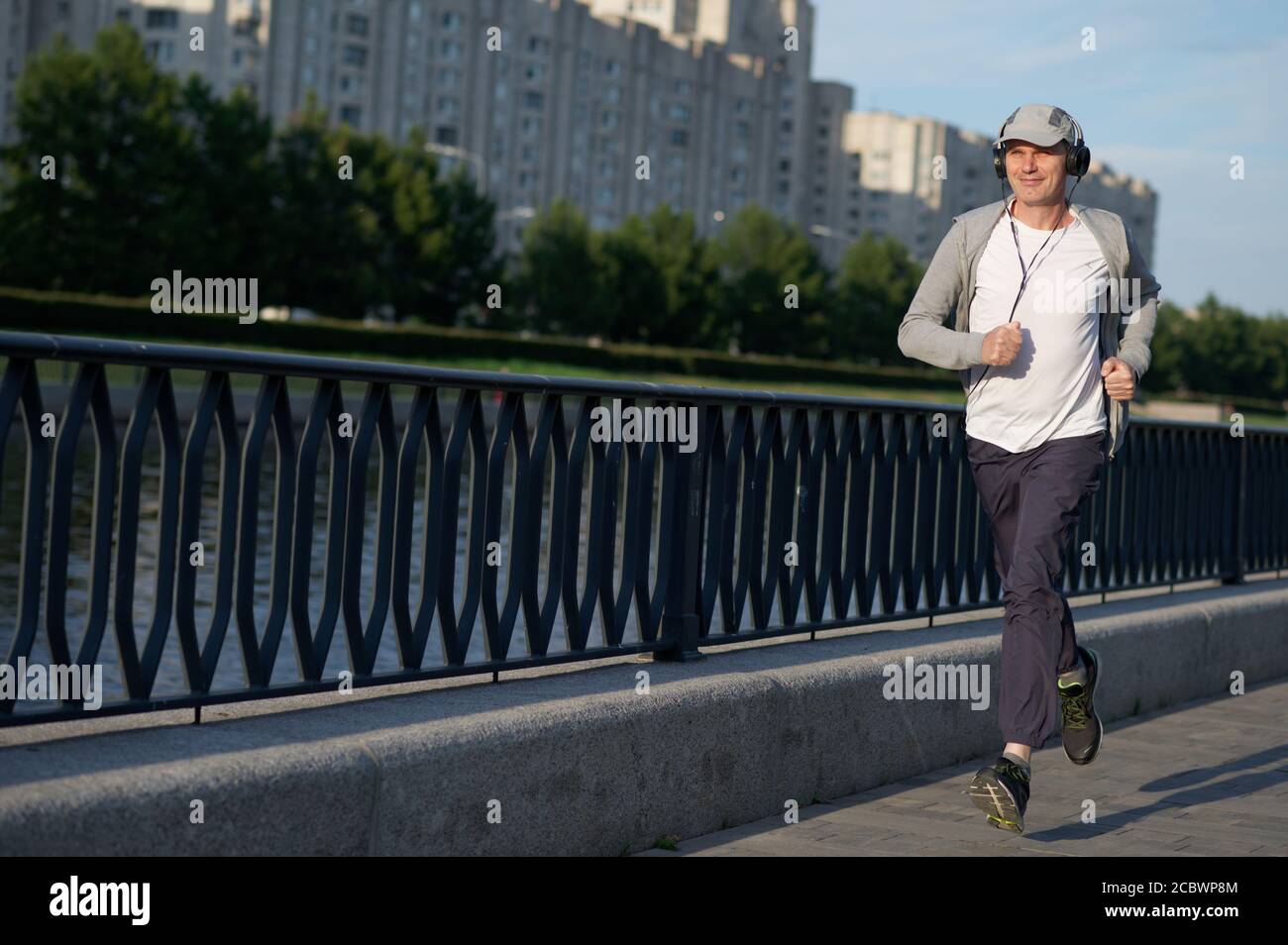 Mature Caucasian man with headphones jogging in the city Stock Photo