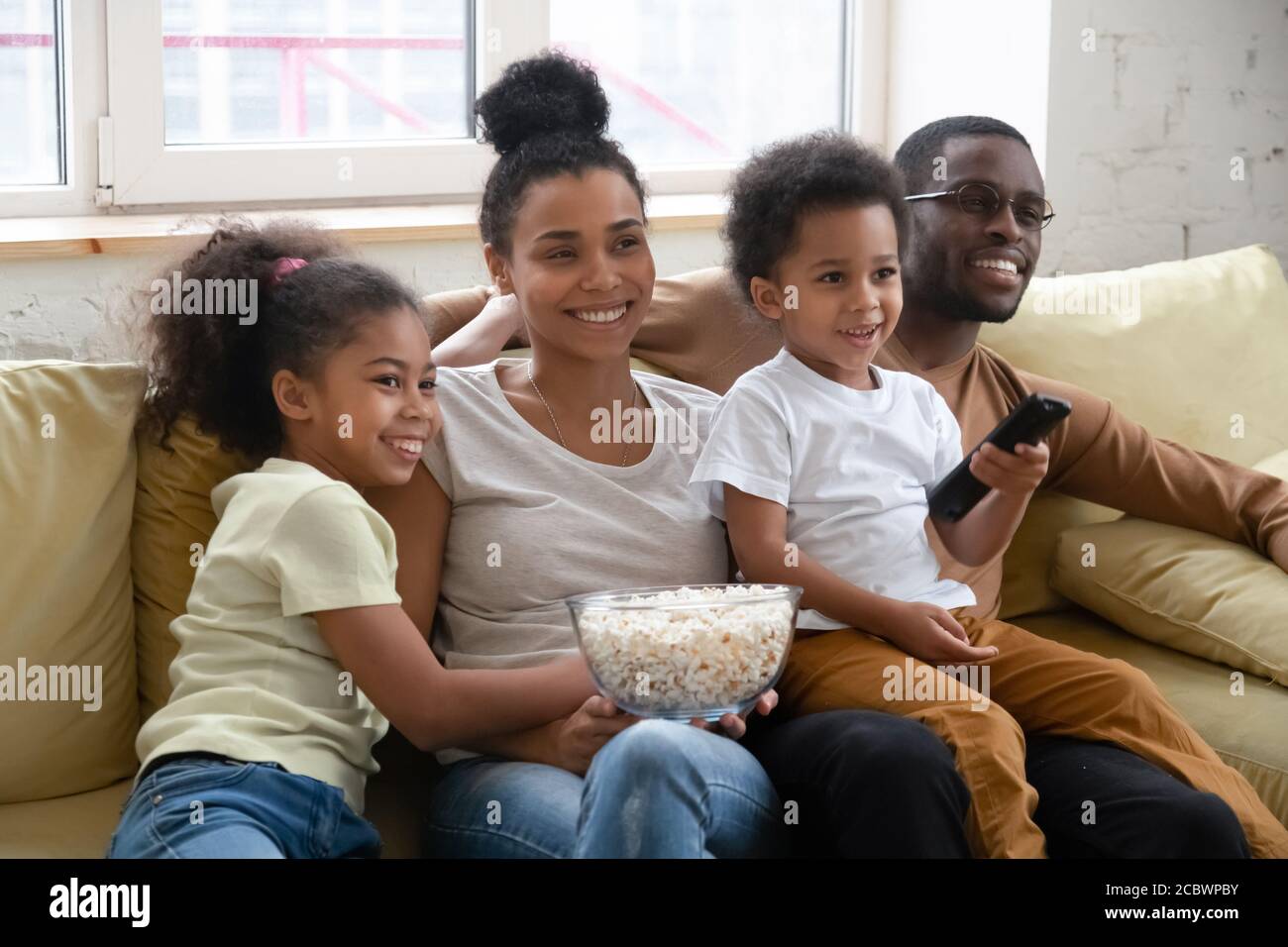 Happy african couple with kids relaxing at home watching tv Stock Photo ...