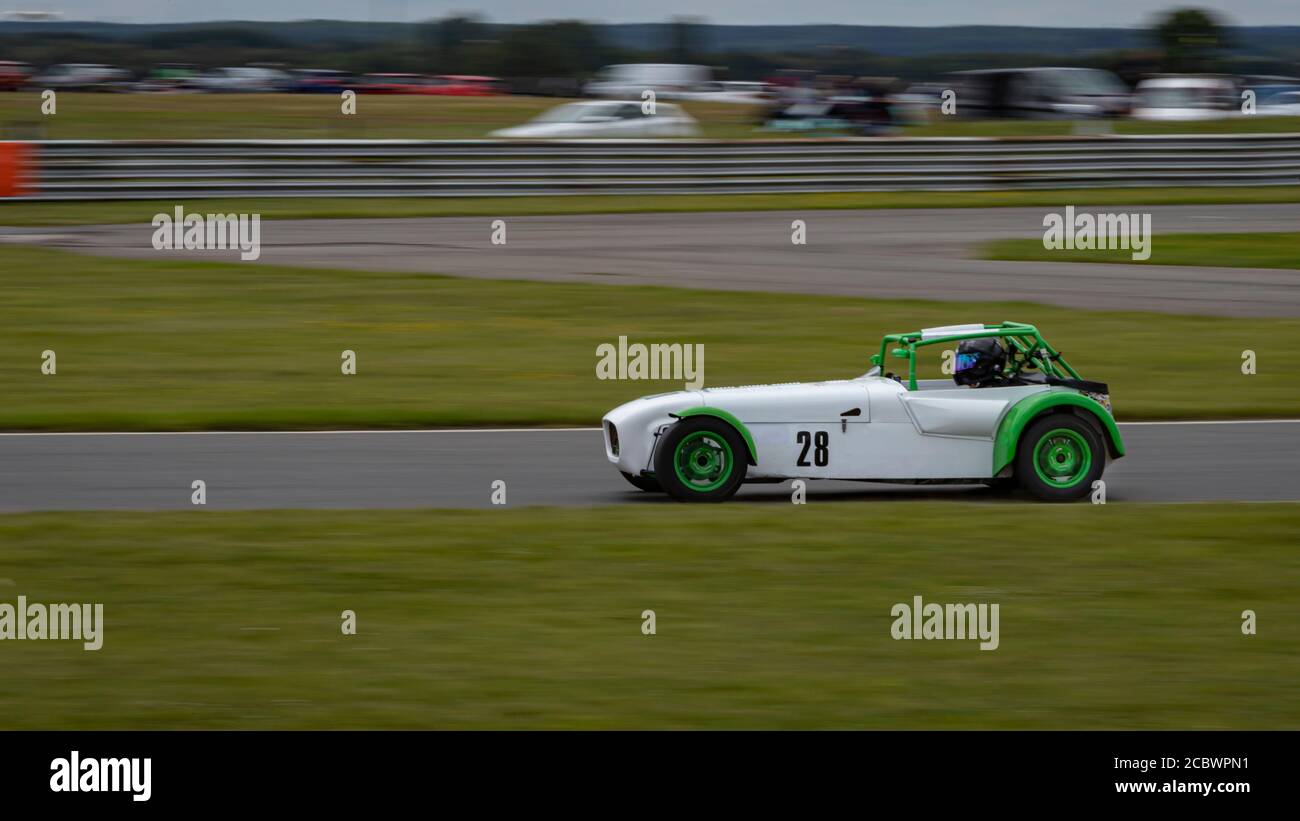 A panning shot of a white and green racing car as it circuits a track. Stock Photo