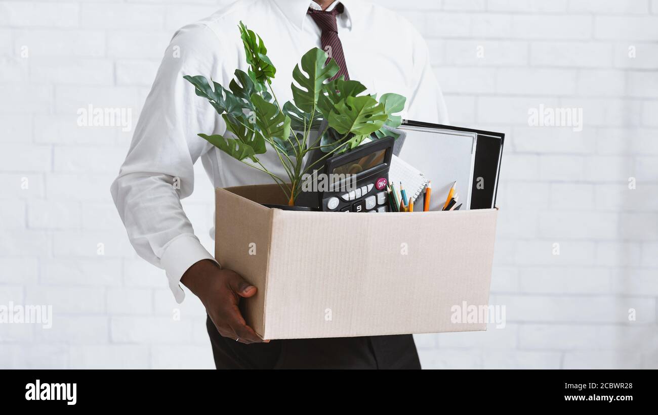 Losing job. Closeup view of African American guy with box of his stuff leaving office Stock Photo