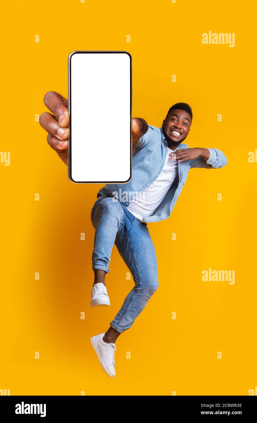 Excited african guy dancing with modern smartphone Stock Photo