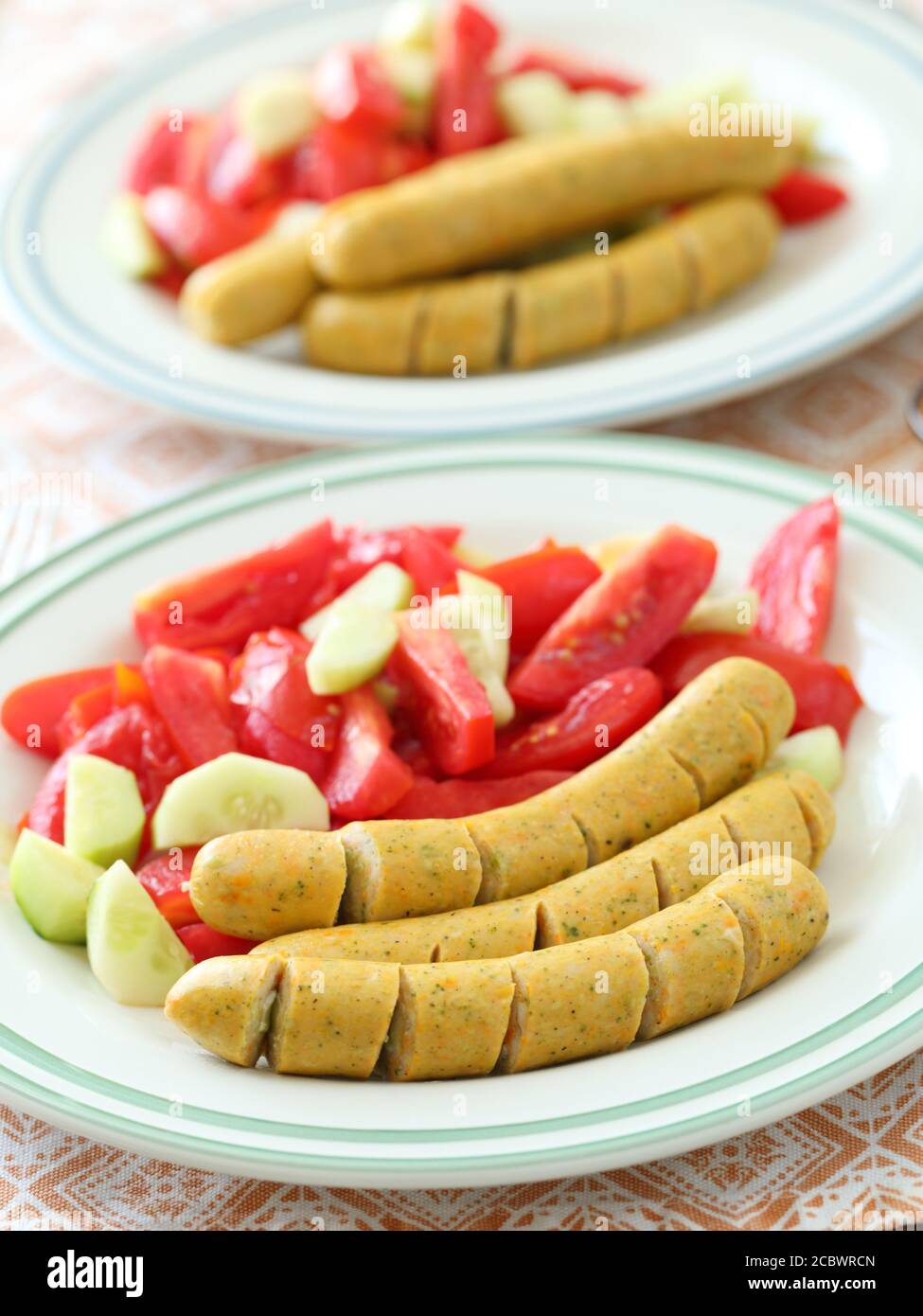Two portion of sausages with tomato and cucumber salad Stock Photo