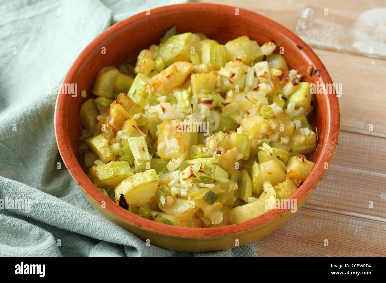 Summer squash and green onion gratin in a baking dish on a rustic table Stock Photo