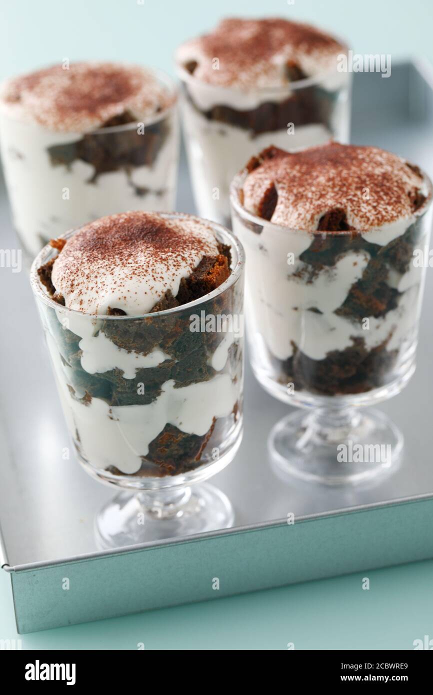 Four portions of the trifle dessert topped with custard and cocoa powder Stock Photo