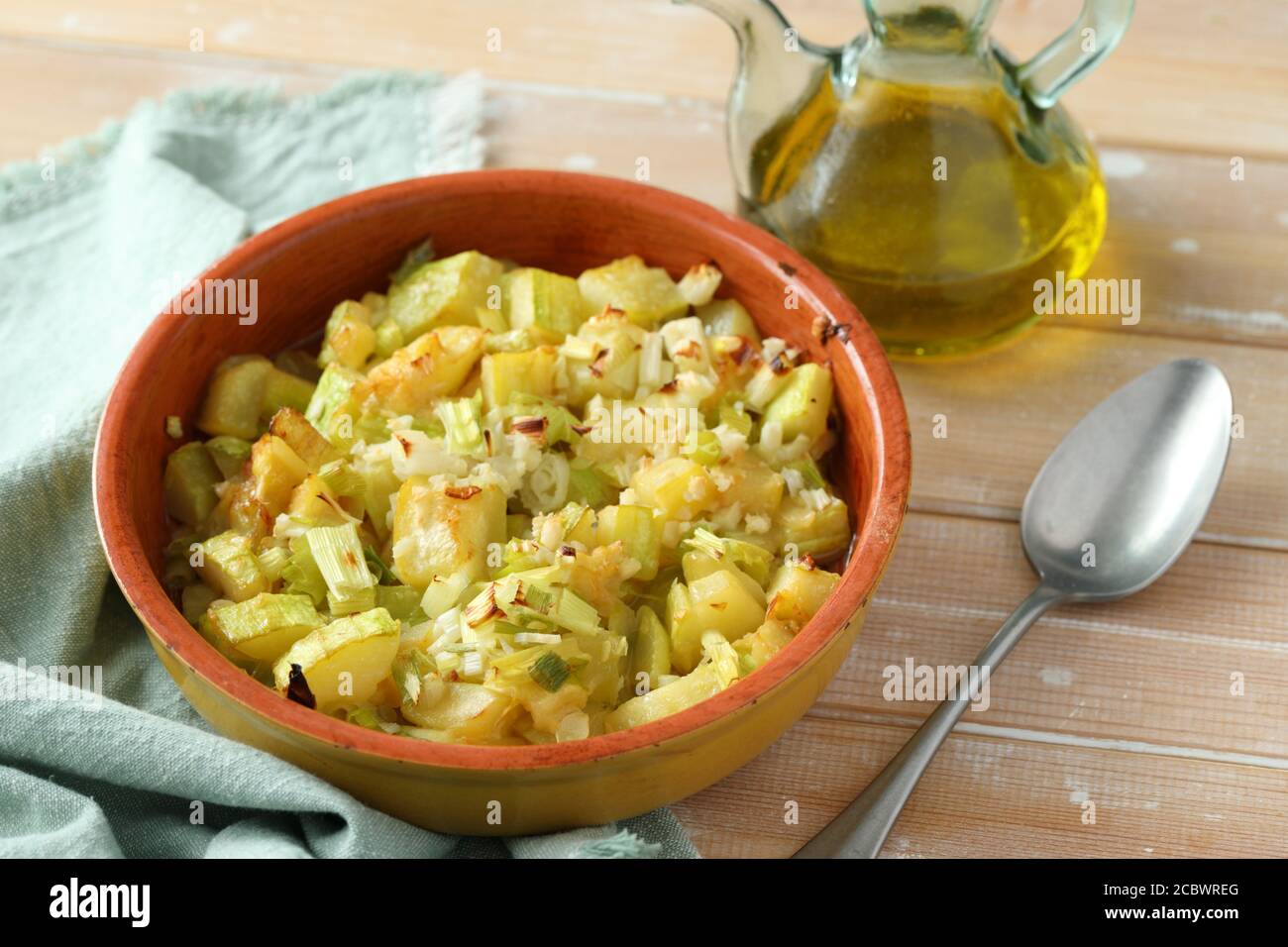 Summer squash and green onion gratin in a baking dish on a rustic table Stock Photo