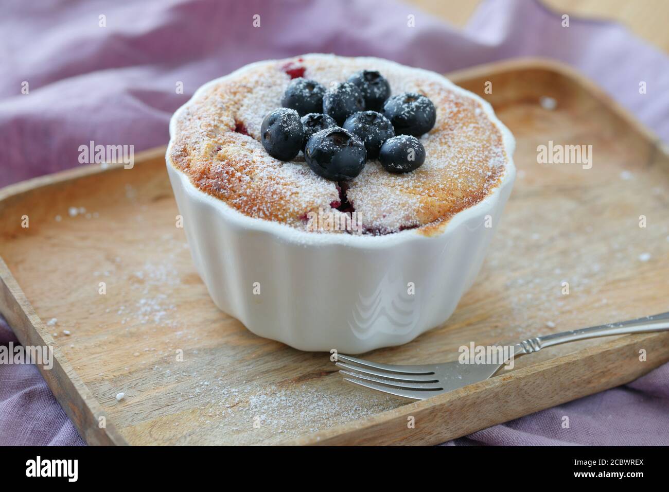 Homemade blueberry muffin in a baking dish topped by powdered sugar Stock Photo