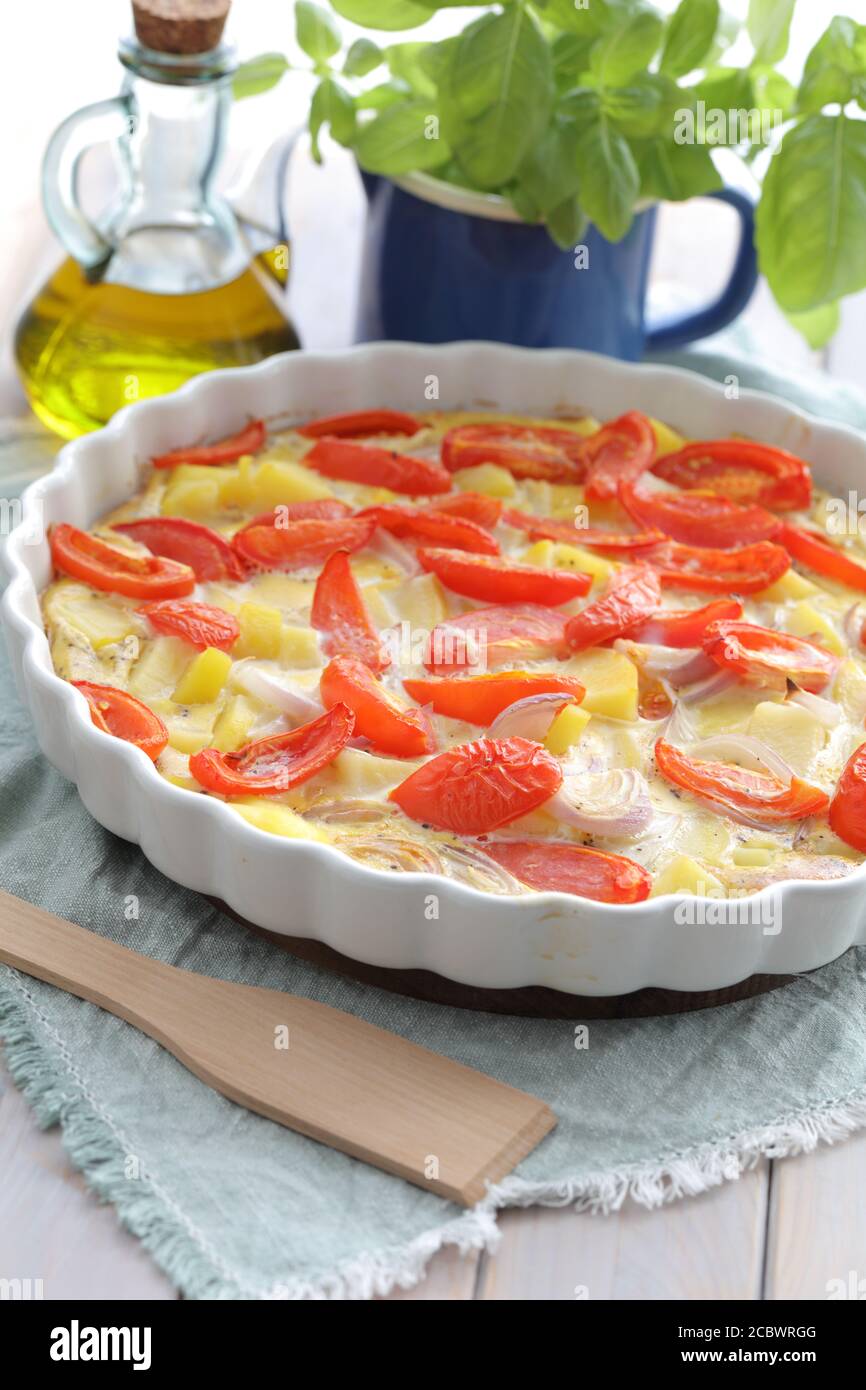 Baked frittata with potato, onion, and tomatoes decorated with green