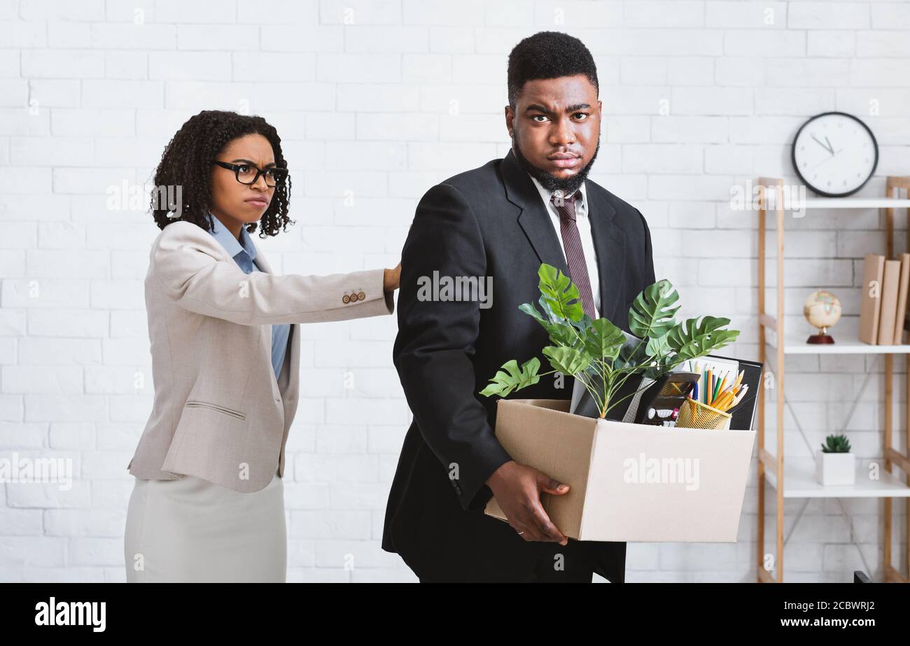 Crisis and unemployment. African American businesswoman firing upset male employee at office Stock Photo