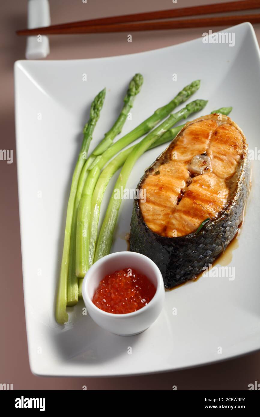 Salmon steak with steamed asparagus and red caviar on a rectangular plate Stock Photo