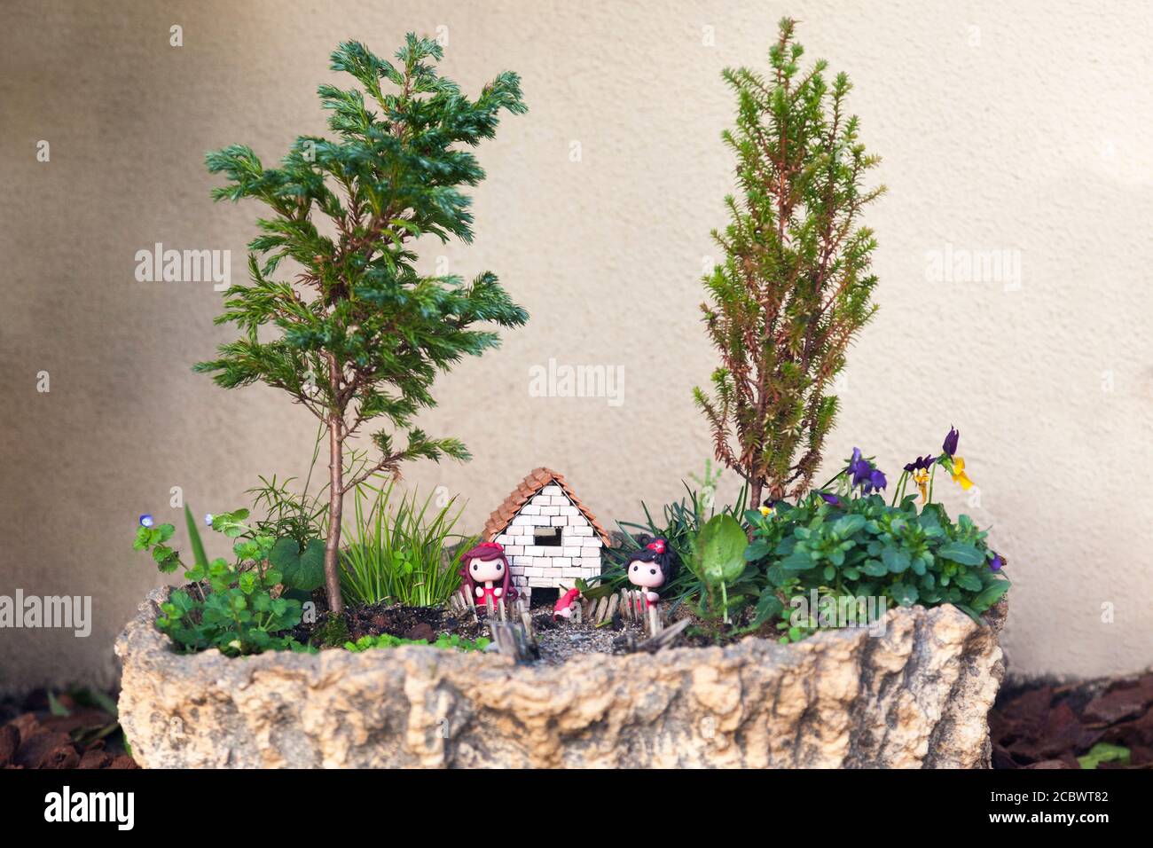 Outdoor fairy mini garden with dolls, trees and a small house Stock Photo