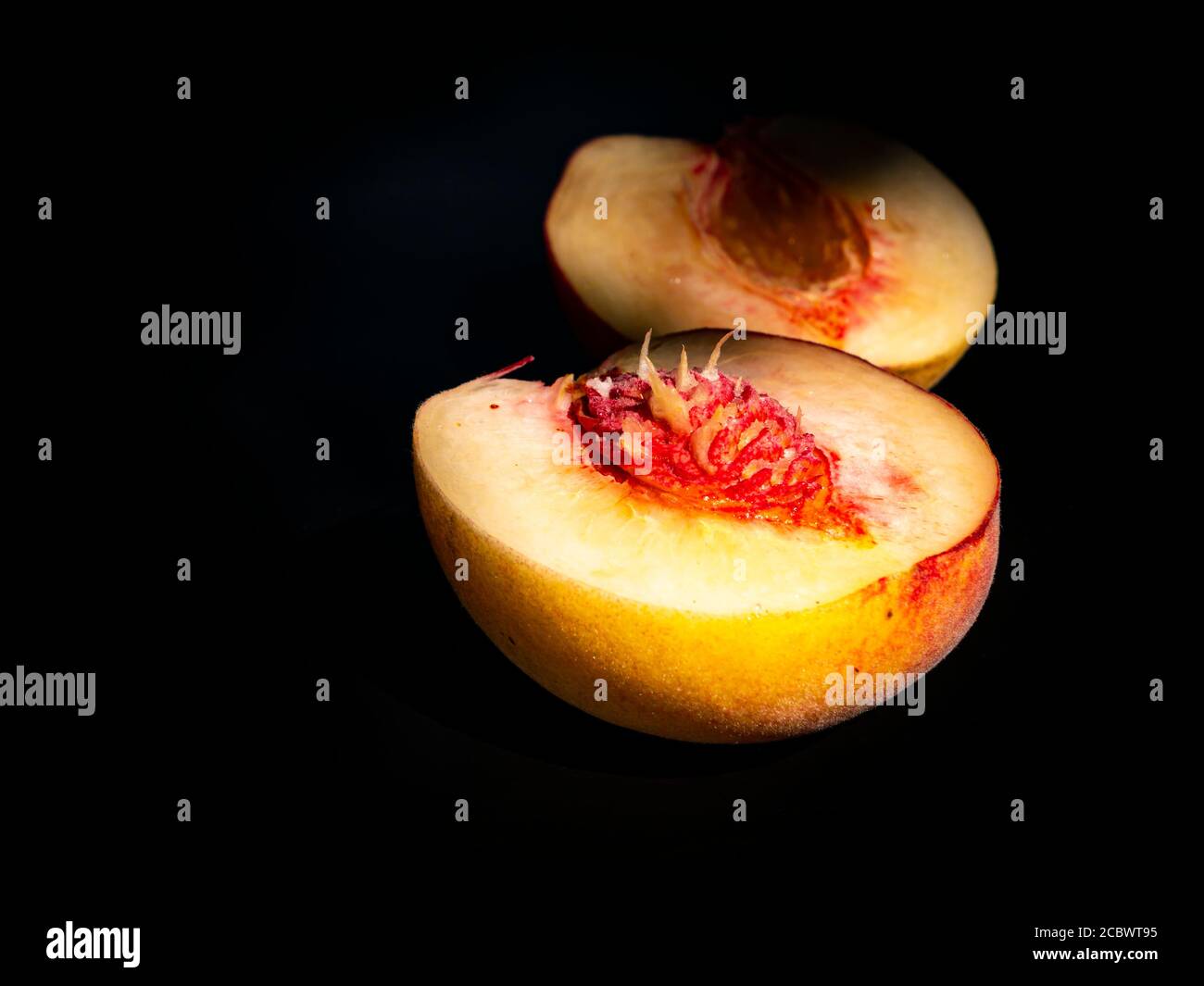 Half peach fruit on a black background. Stock Photo