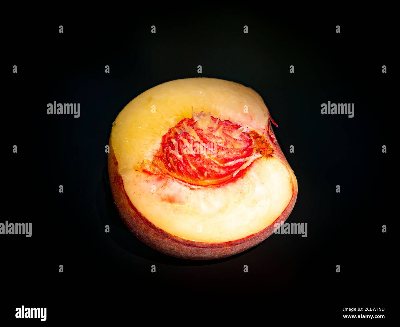 Half peach fruit on a black background. Stock Photo
