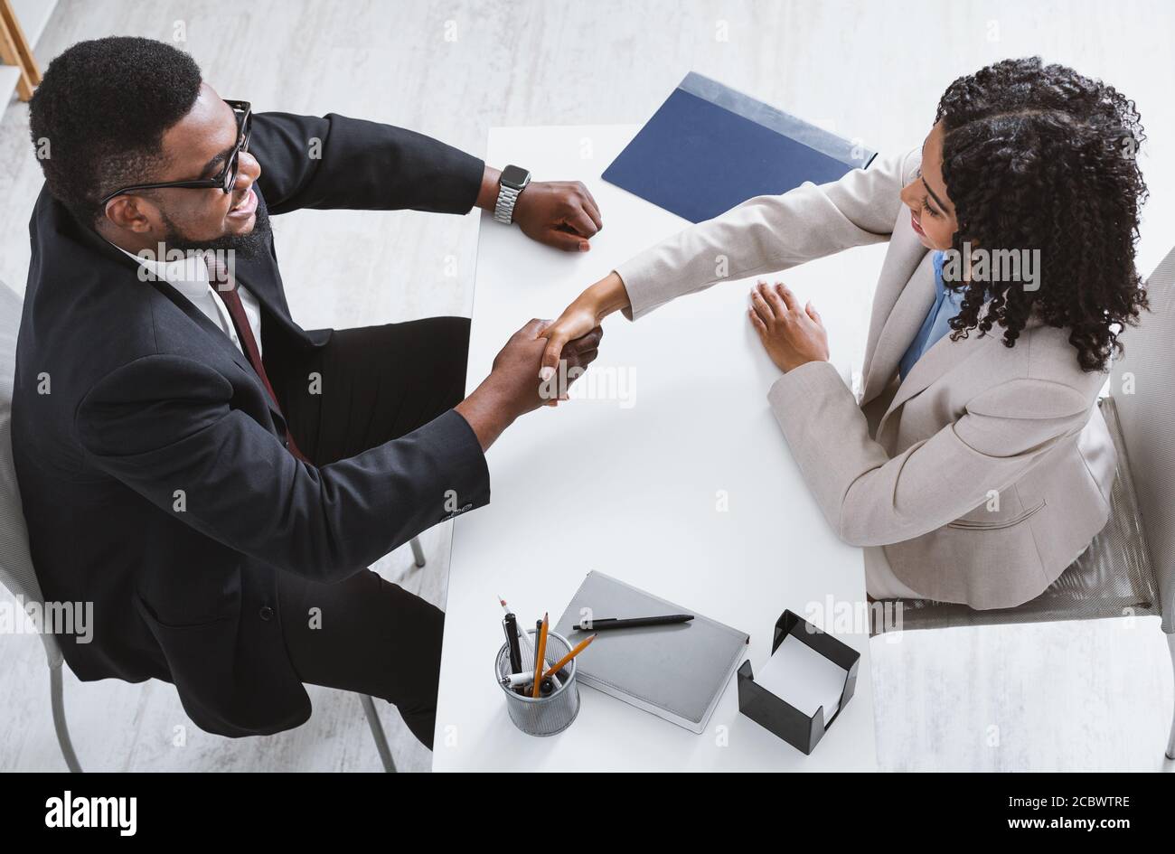 Above view of personnel manager shaking hands with vacancy applicant during job interview at office Stock Photo