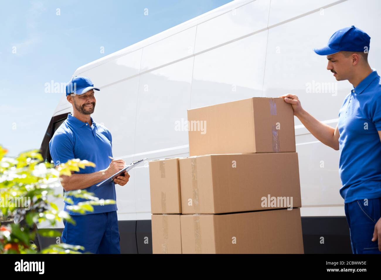 Van Courier And Professional Movers Unload Truck Stock Photo