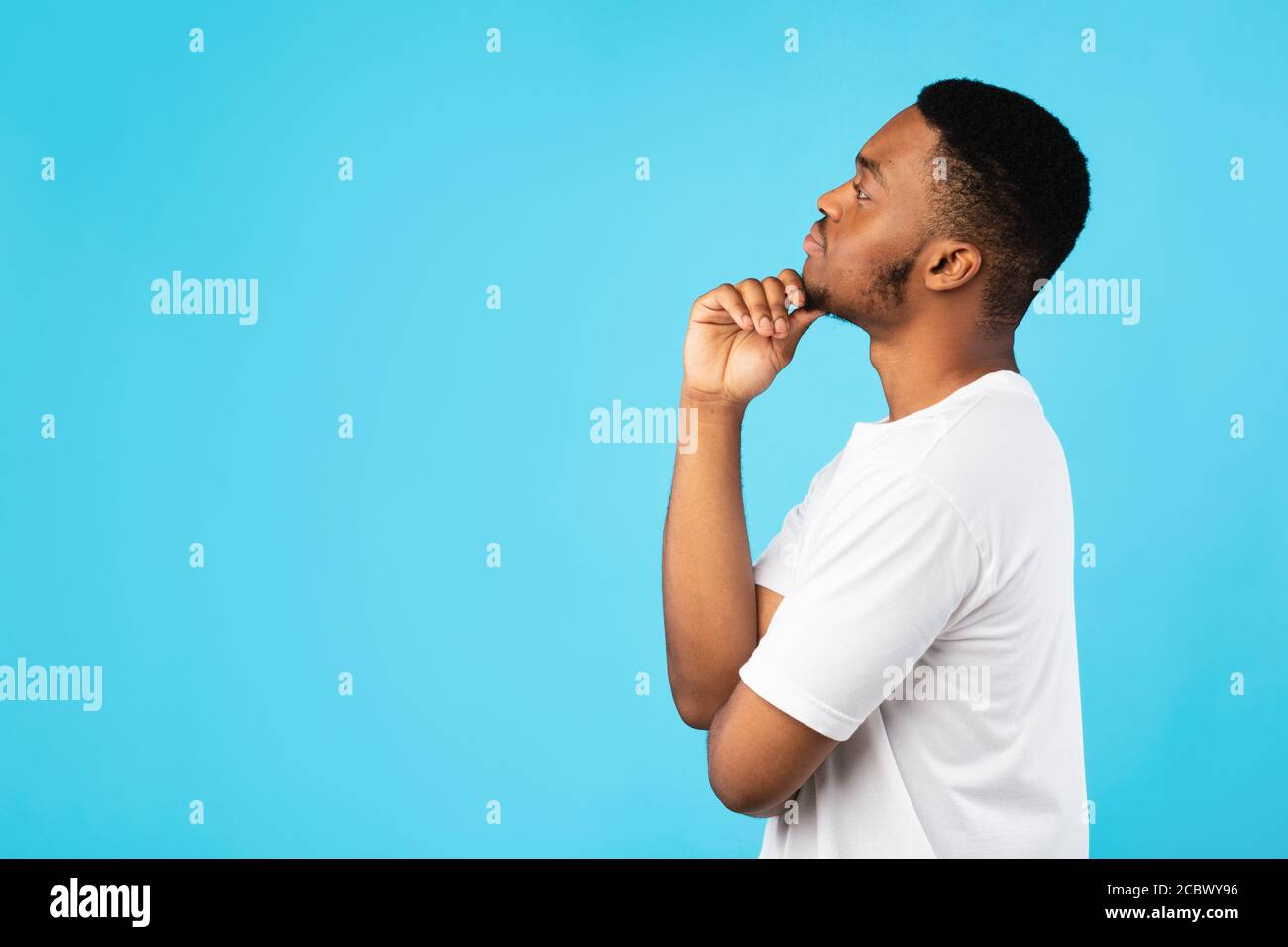 Thoughtful Black Guy Thinking Looking Aside Standing On Blue Background Stock Photo