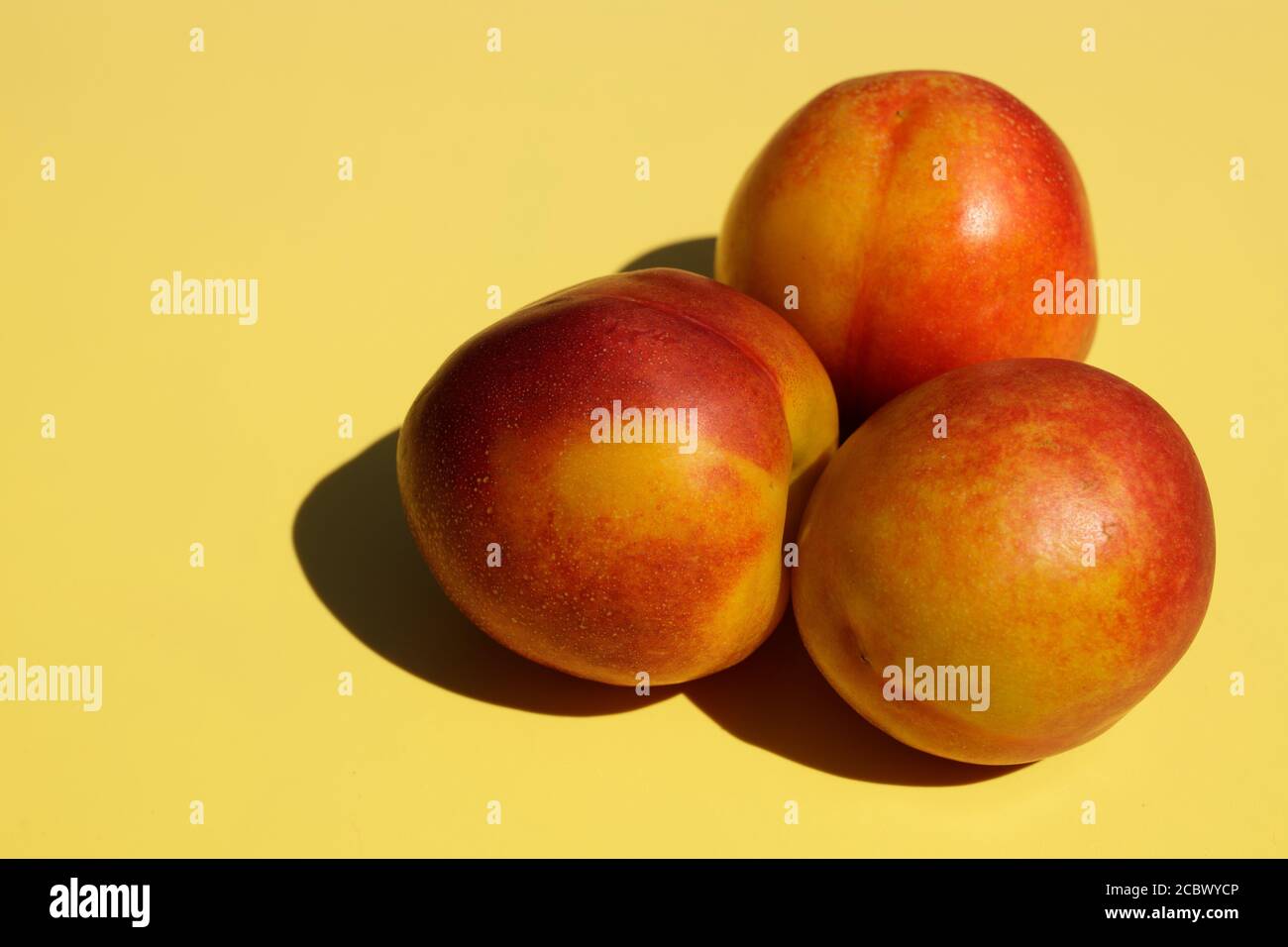 Three ripe nectarines on yellow background. Stock Photo