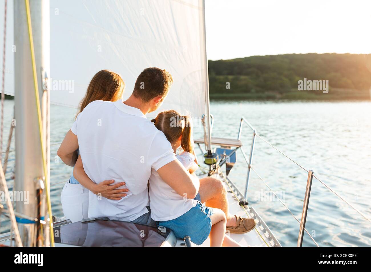 Family Enjoying Yacht Tour Sitting On Deck Sailing In Sea Stock Photo