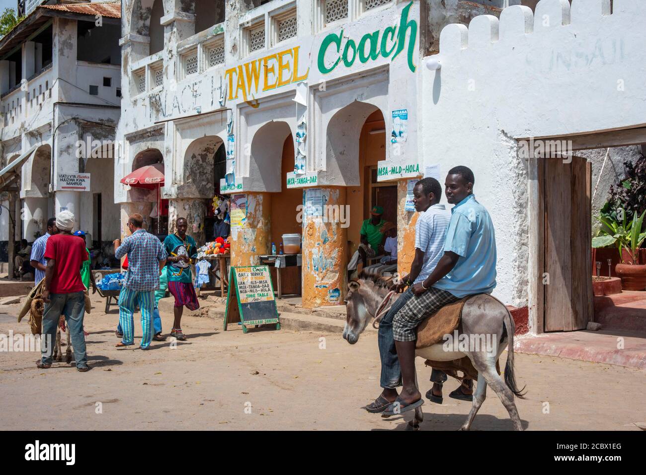 Men riding donkeys on the main street of Lamu town in Lamu Island, Kenya. Stock Photo