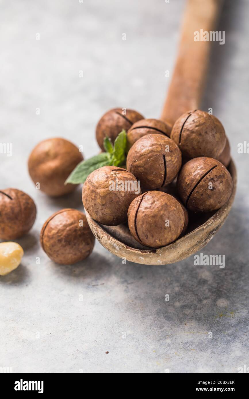 Pile macadamia nuts open kernels and shells in spoon on stone background. Stock Photo