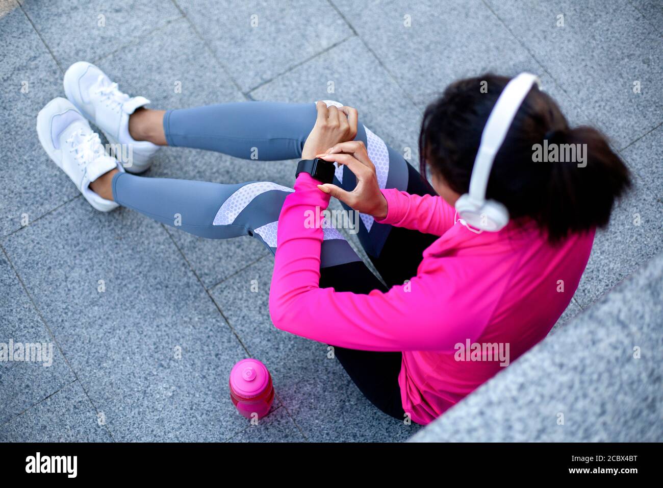 Black sporty girl with headset checking on fitness bracelet Stock Photo