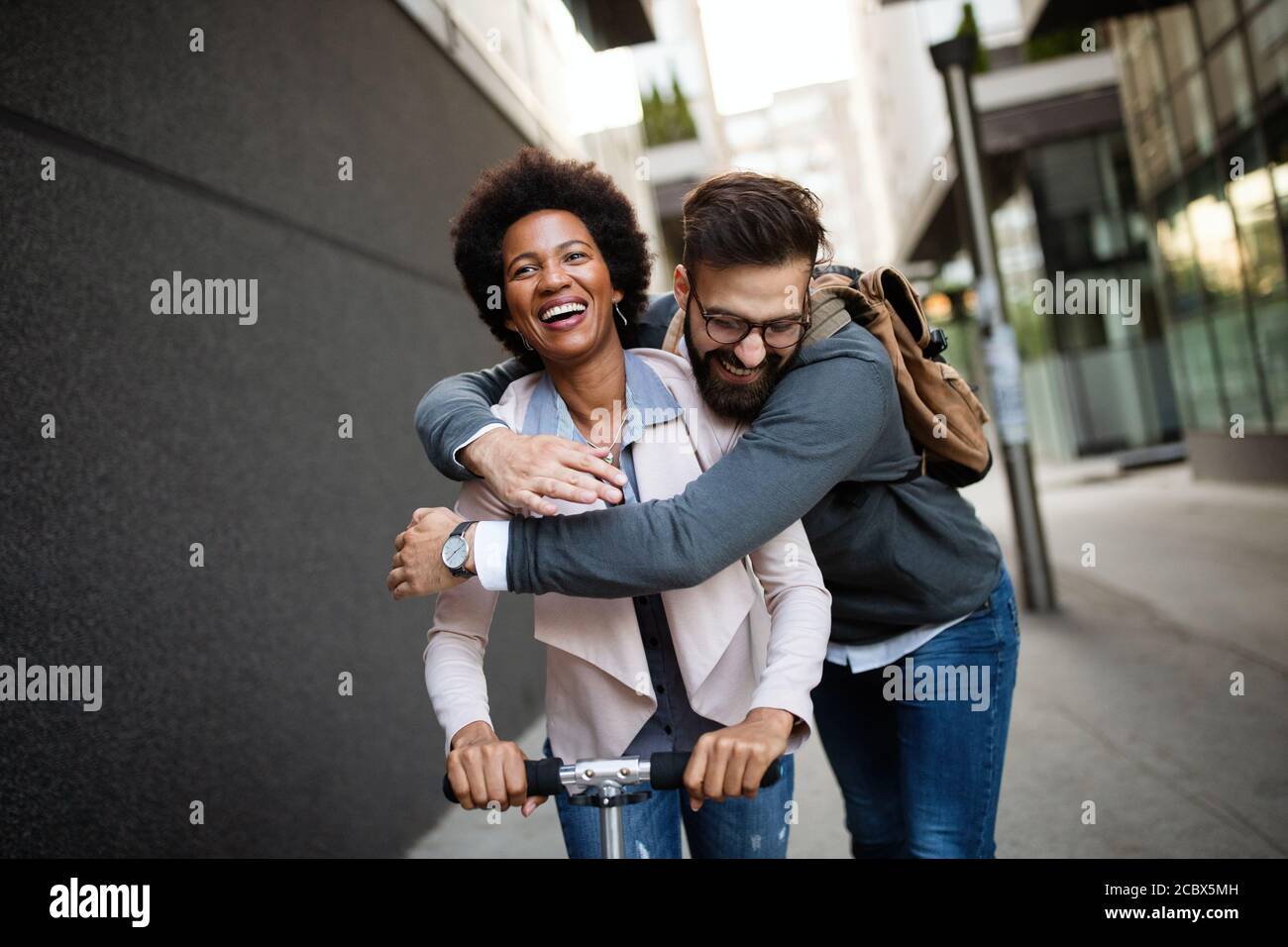 Young couple on vacation having fun driving electric scooter in the city. Stock Photo