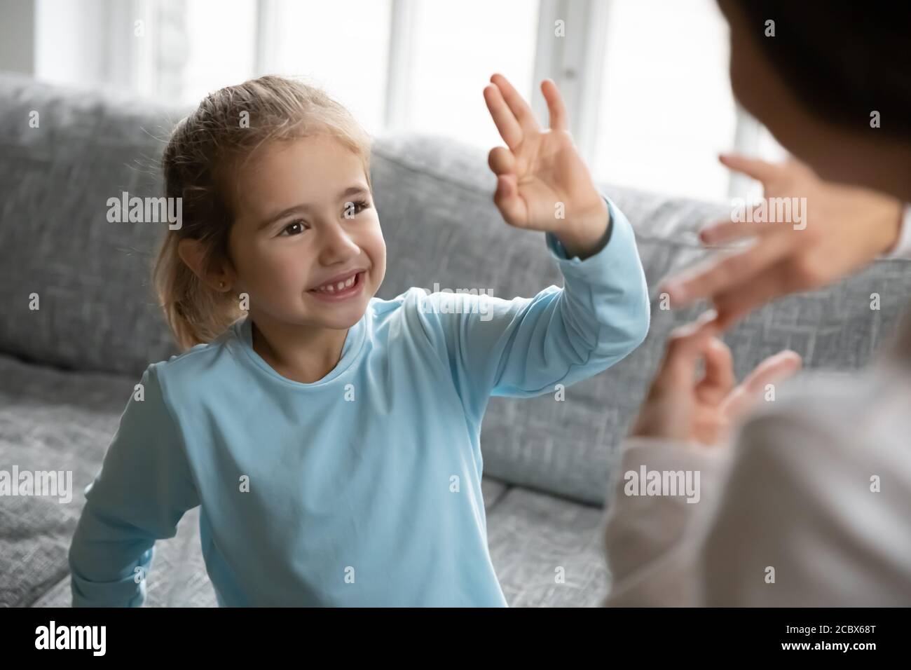 Happy little girl with hearing impairment enjoying communicating with mother. Stock Photo