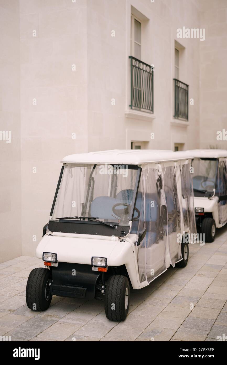Golf cart with a transparent awning parked in the parking lot near the hotel. Stock Photo