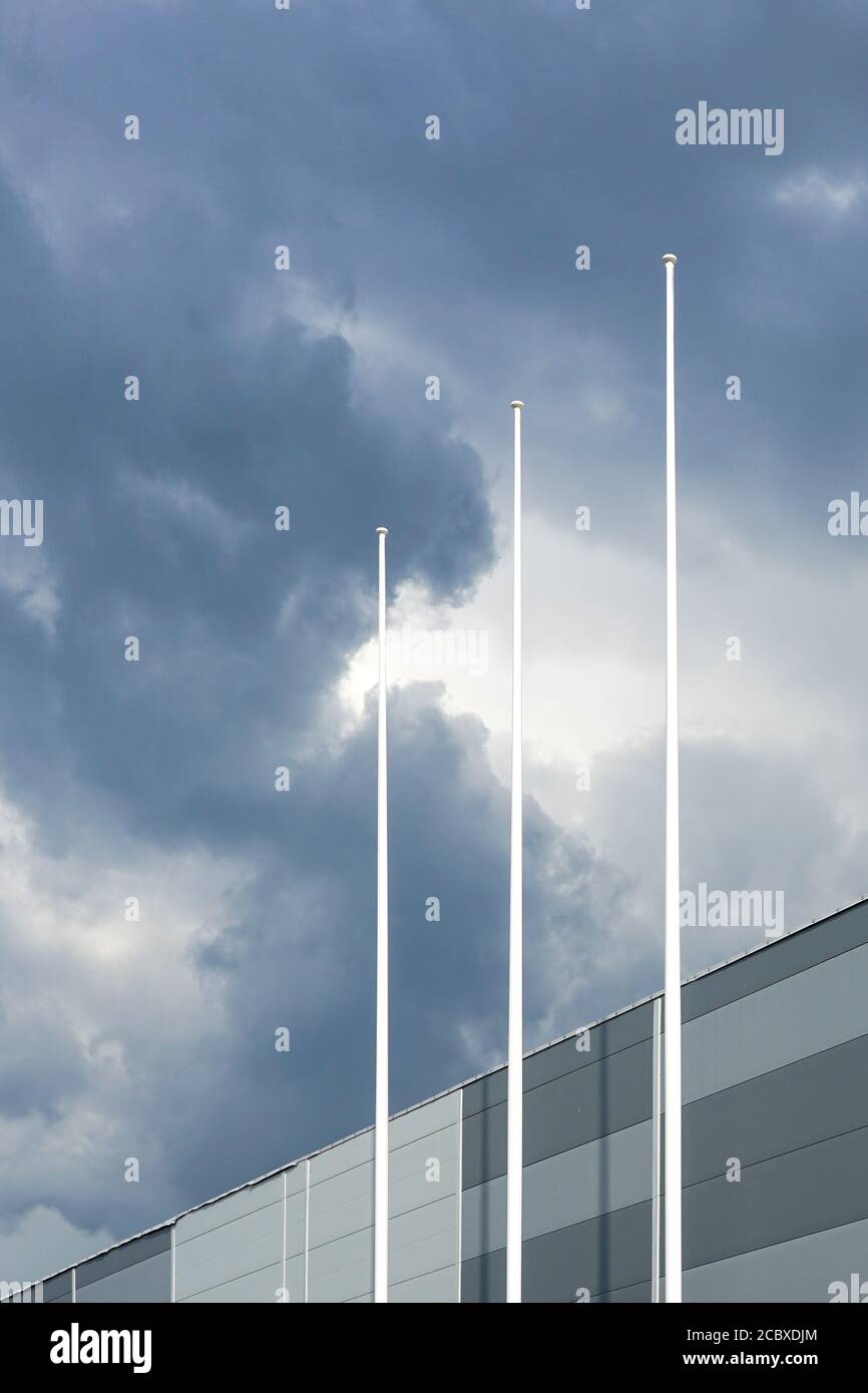 the facade of a new building and three flagpoles without flags on a ...