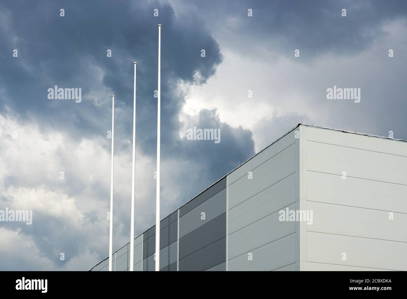 the facade of a new building and three flagpoles without flags on a ...