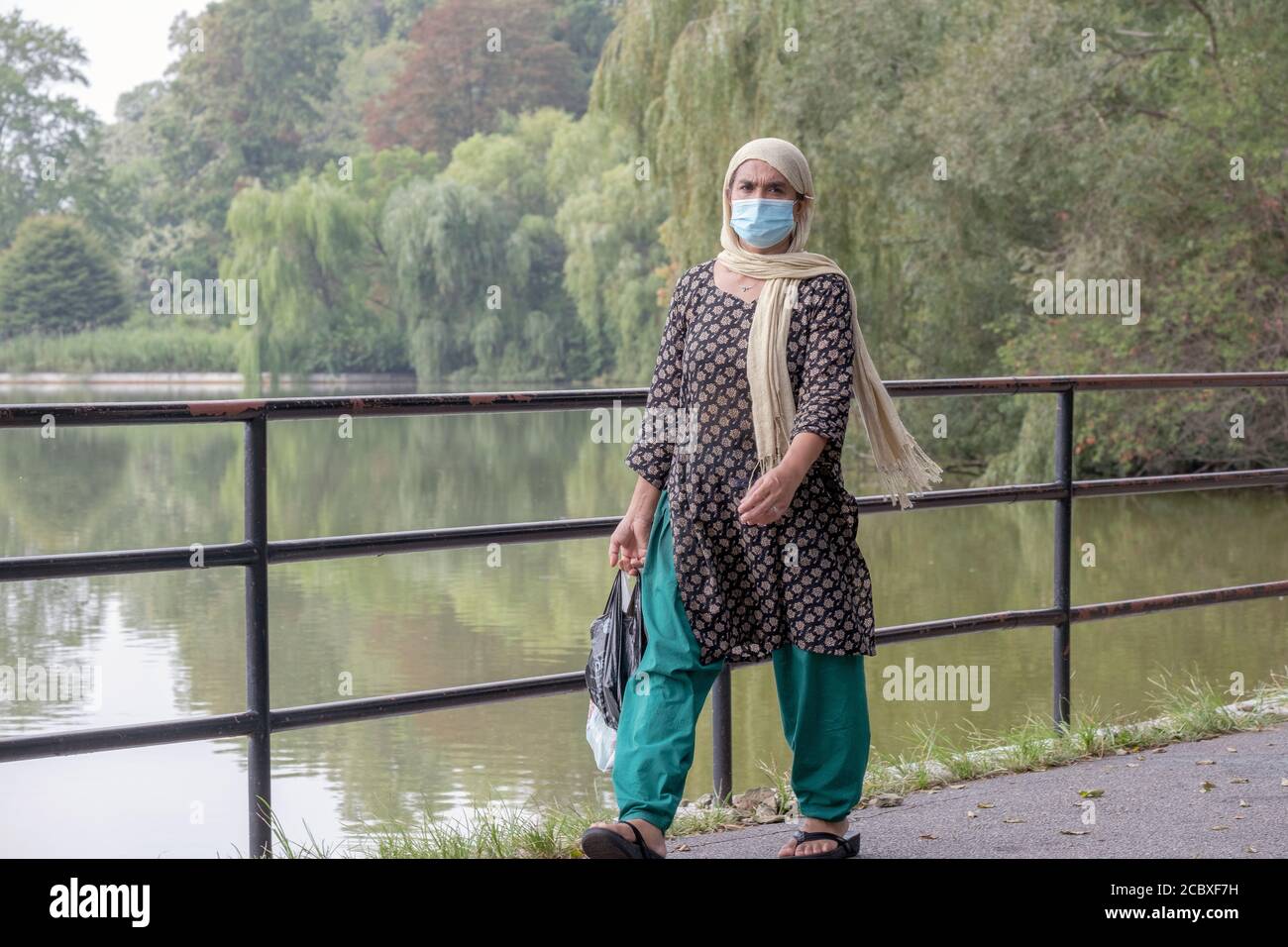A Muslim woman wearing a headscarf walks alongside the lake in Kissena Park, Flushing, New York City Stock Photo