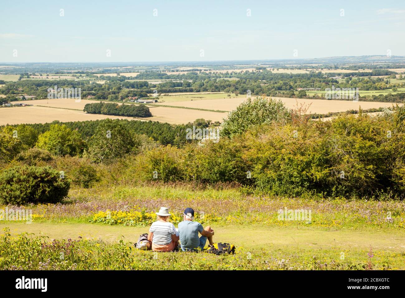 Man and woman couple sitting on Watlington hill admiring the view over the Oxfordshire Chilterns landscape England UK Stock Photo