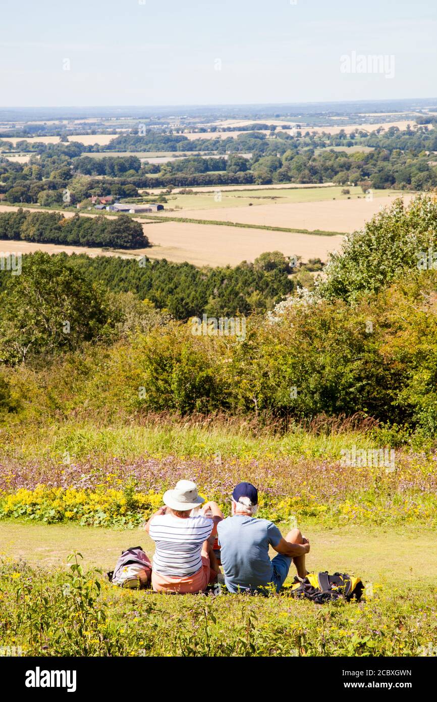 Man and woman couple sitting on Watlington hill admiring the view over the Oxfordshire Chilterns landscape England UK Stock Photo