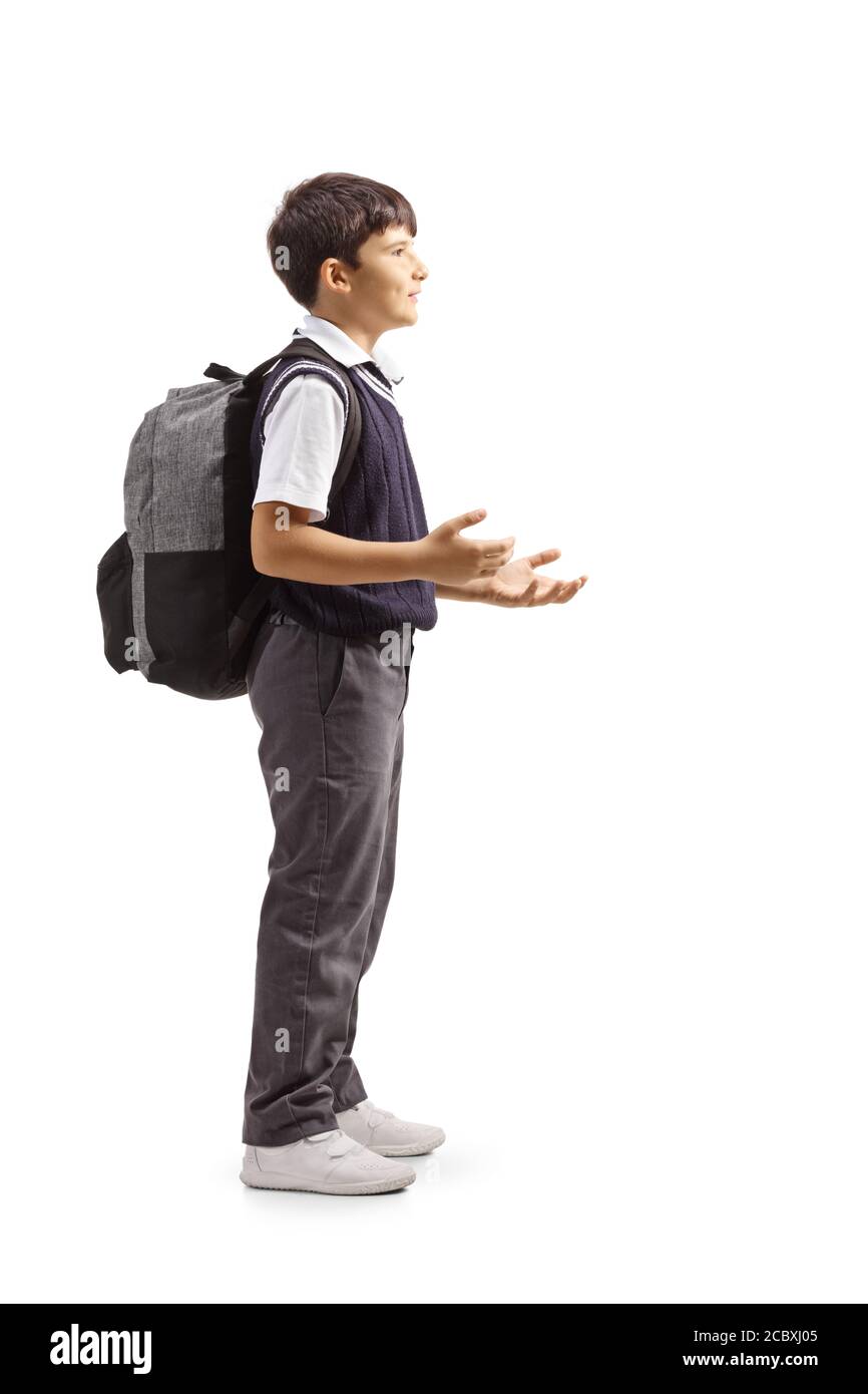 Full length profile shot of a schoolboy standing, gesturing with hands and carrying a backpack isolated on white background Stock Photo