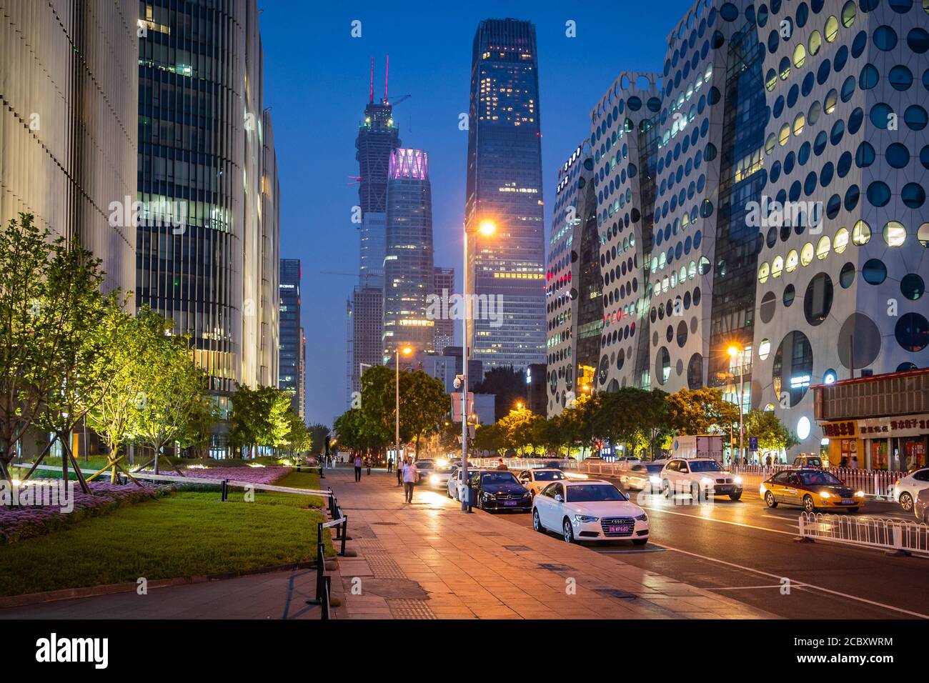 Street view of Beijing, China, showing traffic, pedestrians and modern office buildings at night in the Beijing Central Business District. Stock Photo