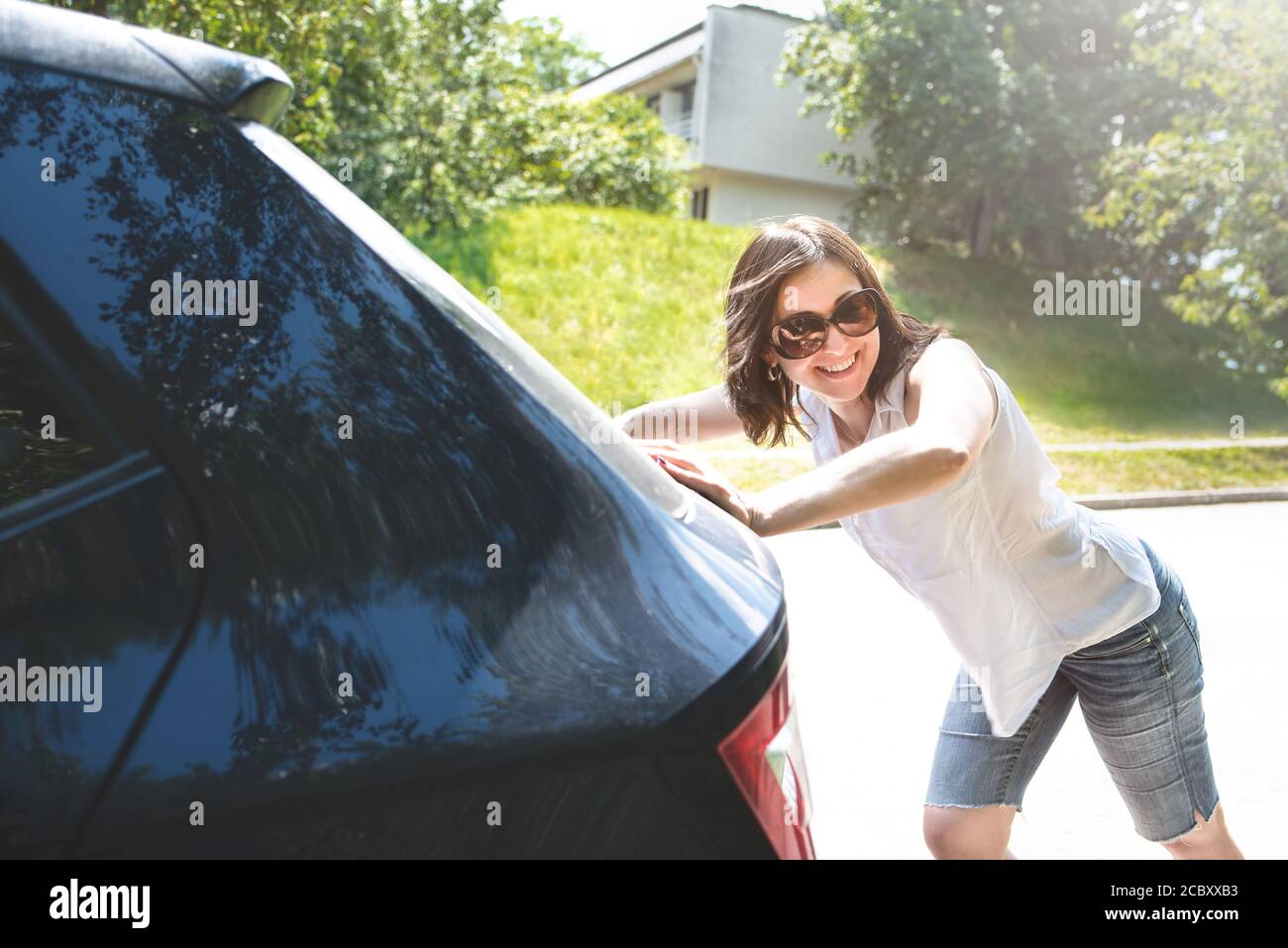 woman pushing broken car while her boyfriend is driving Stock Photo