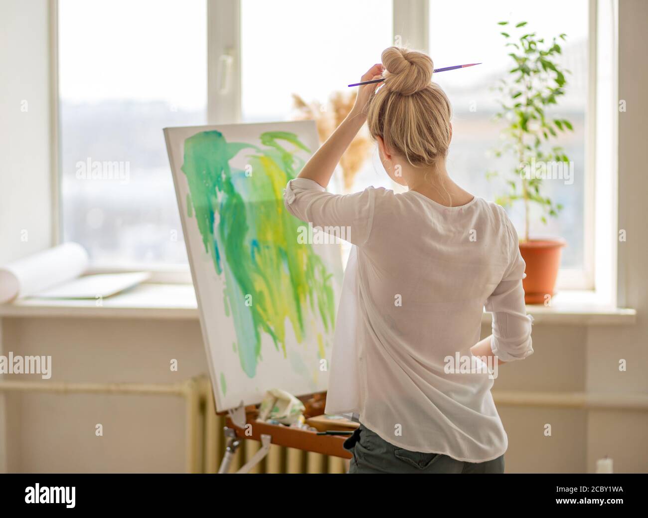 blond student learning basic painting skills. close up back view photo