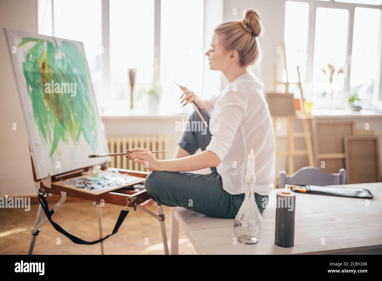 female art-worker at workplace . brushwork. the brush. full length side