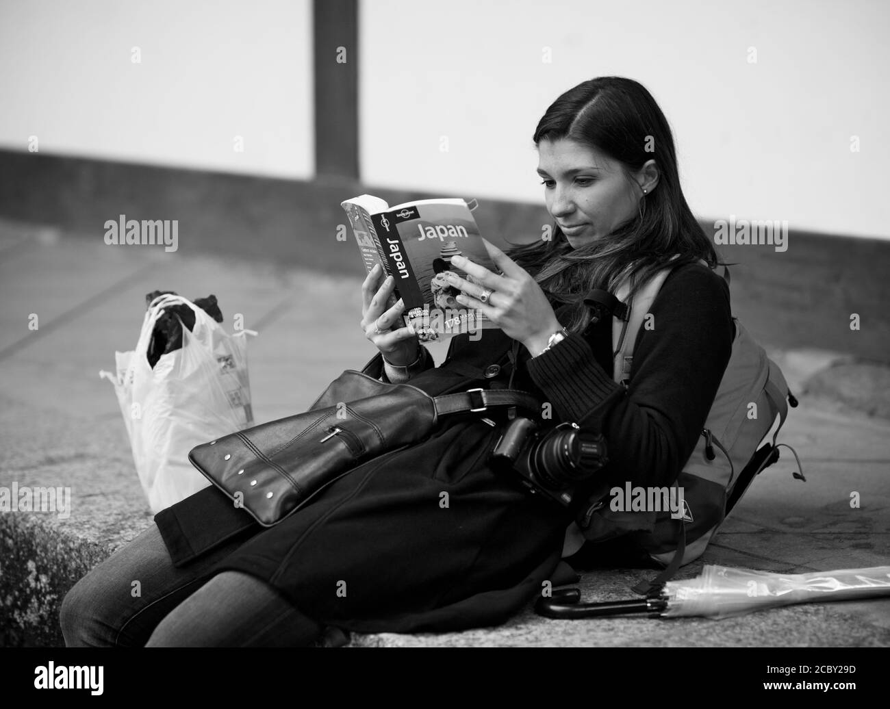 Occidental tourist having a rest and reading Lonely Planet touristic guide at the gate of Todai-Ji temple, Nara, Japan 2012 Stock Photo