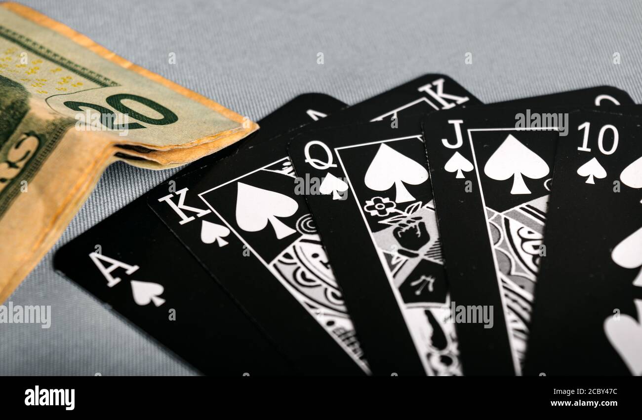 Close up shot of folded dollar bills next to a royal flush at a poker game Stock Photo