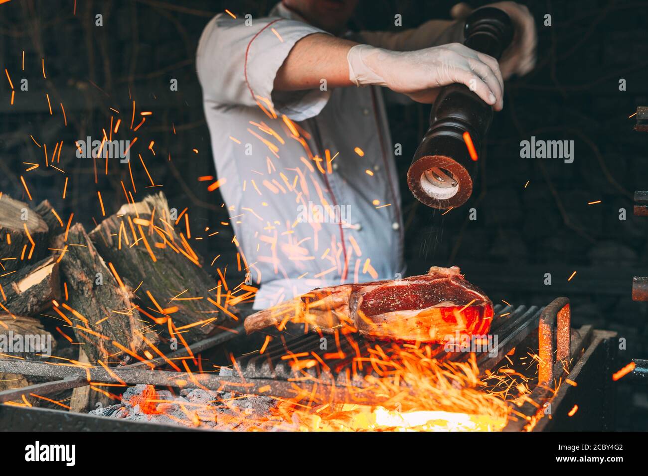 Cooking Steak in a stone oven. Chef pepper the steak on fire Stock ...