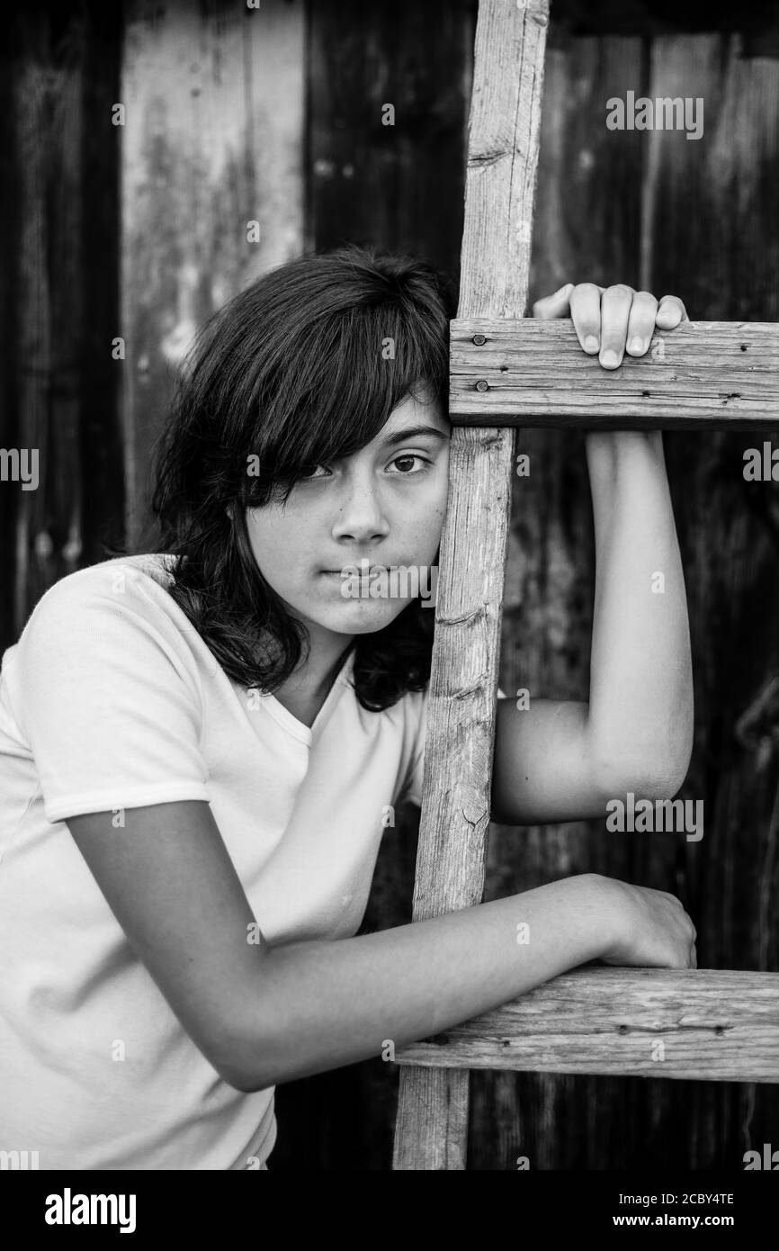 Black And White Portrait Of A Teenage Girl Near The Wooden Village