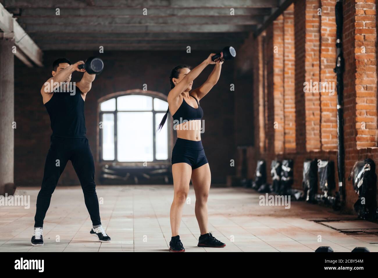 man and woman throwing weight in the sport center. full length photo