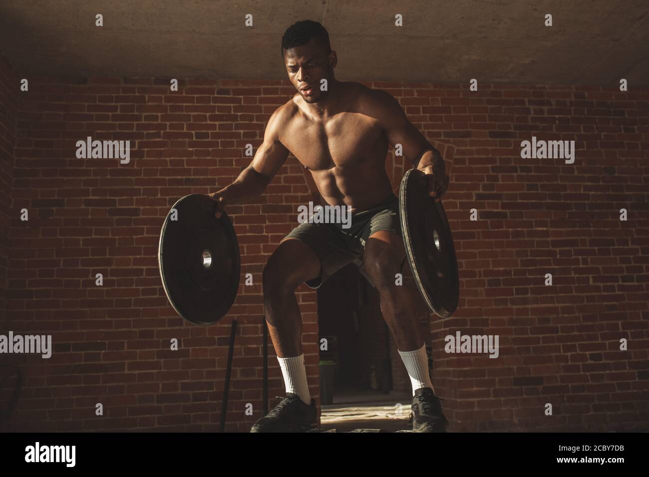 Athletic dark skinned fitness coach working out with crossfit