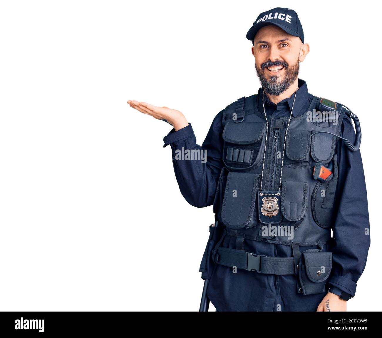 Young handsome man wearing police uniform smiling cheerful presenting and pointing with palm of hand looking at the camera. Stock Photo