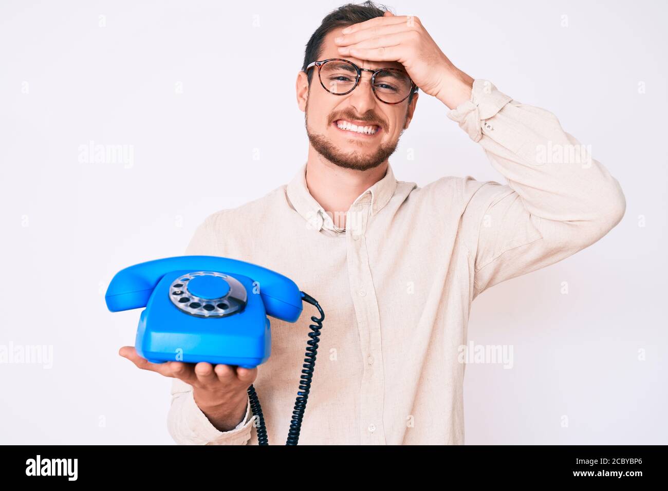 Young handsome man holding vintage telephone stressed and frustrated with hand on head, surprised and angry face Stock Photo