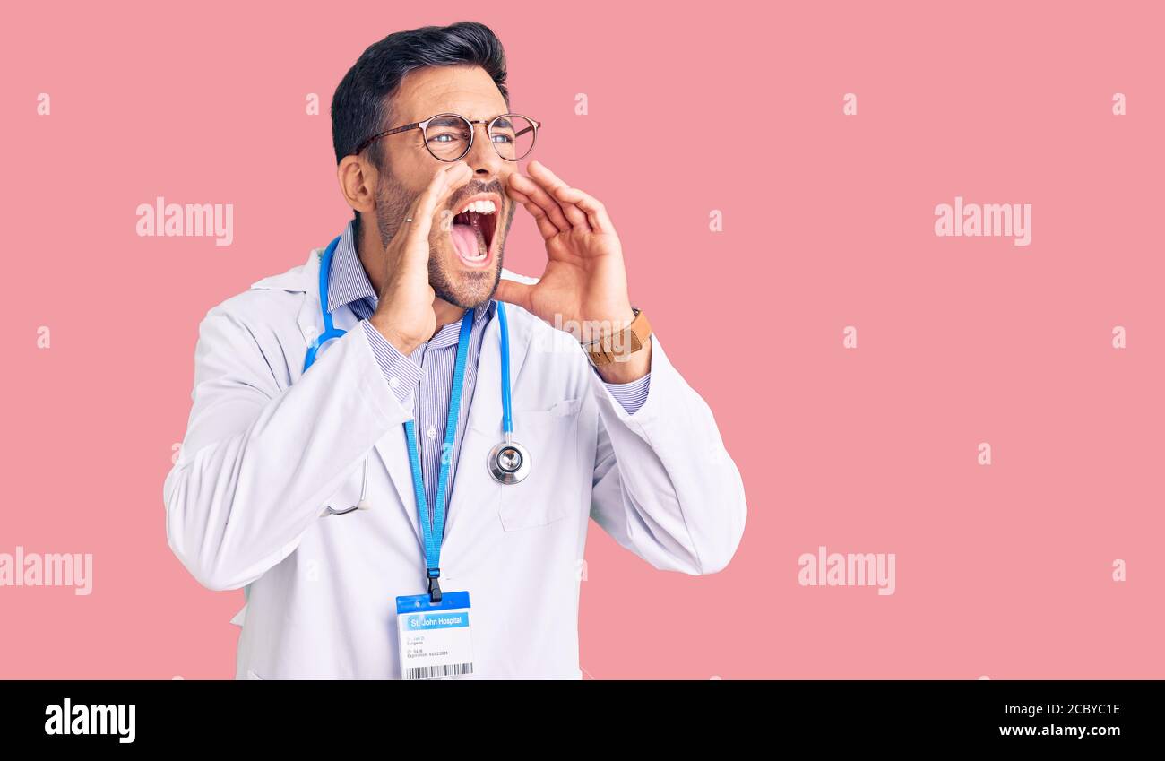 Young hispanic man wearing doctor uniform and stethoscope shouting ...
