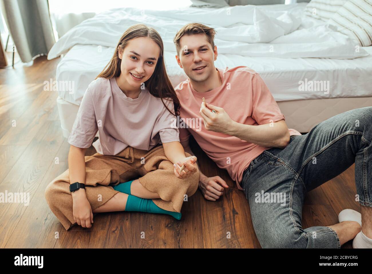 young caucasian couple, man and woman use cannabis weed, catch a buzz together at home. drugs, marijuana, hemp medicine, junkie, ganja concept Stock Photo